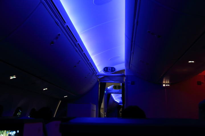 暗くなった機内の天井をやわらかいブルーのライトが照らしている写真